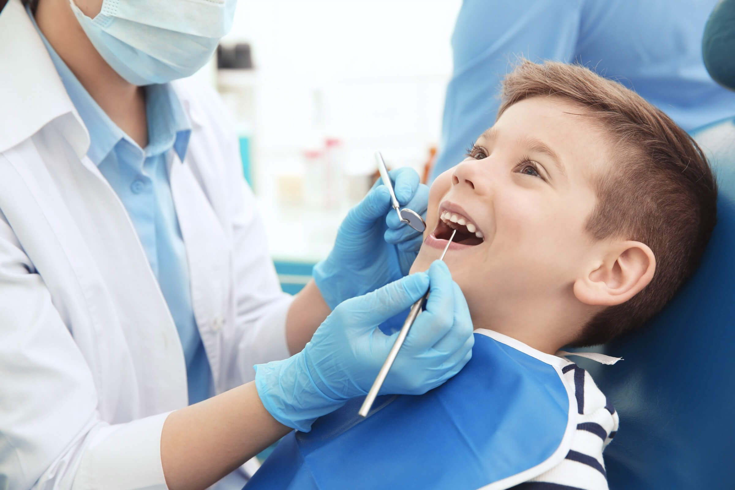 Врач лечащий кариес. Фторирование зубов у детей. Ребенок у стоматолога. Осмотр ребенка у стоматолога.
